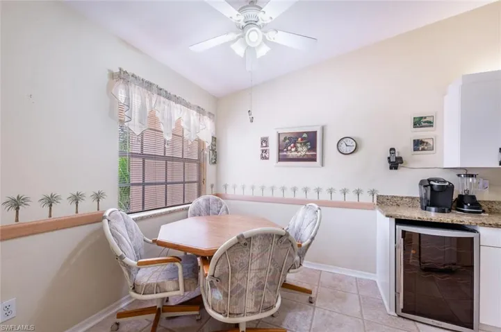 Dining area with light tile patterned floors, wine cooler, a ceiling fan, and baseboards