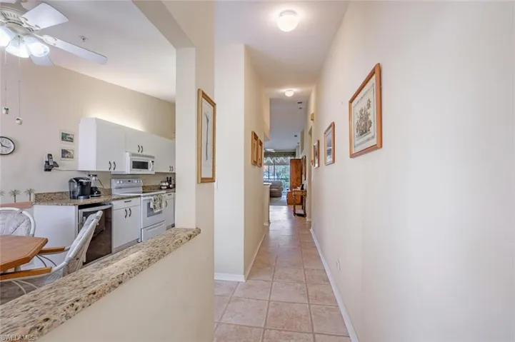 Hall with light tile patterned flooring and baseboards