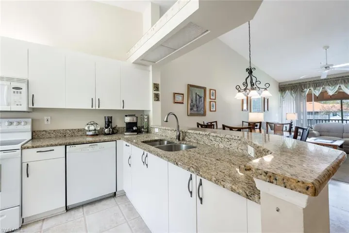 Kitchen with white appliances, a ceiling fan, open floor plan, a peninsula, and a sink