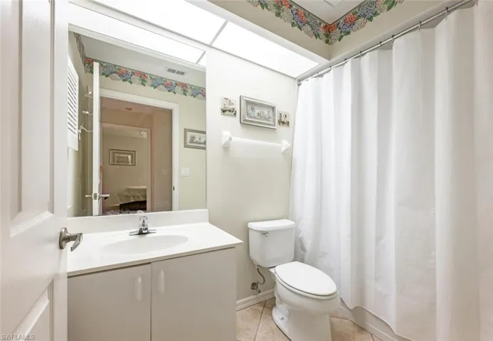 Full bath featuring visible vents, toilet, vanity, a shower with curtain, and tile patterned floors