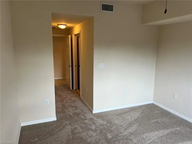 Empty room with baseboards, visible vents, and carpet floors