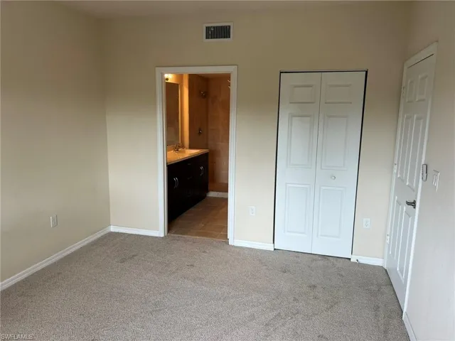 Unfurnished bedroom with baseboards, a closet, light carpet, visible vents, and a sink