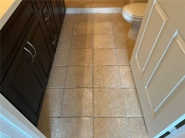 Bathroom with stone tile flooring, toilet, and baseboards