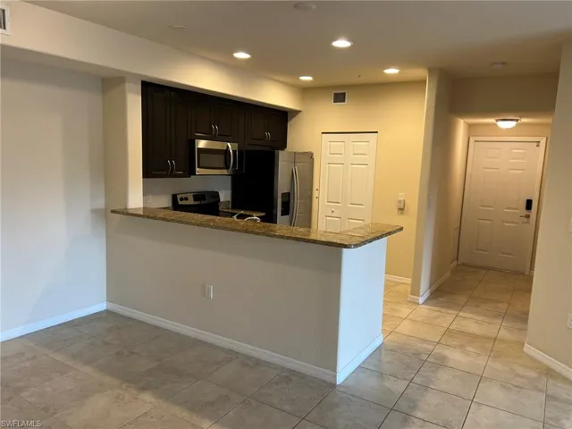 Kitchen with dark stone counters, light tile patterned floors, visible vents, recessed lighting, and appliances with stainless steel finishes
