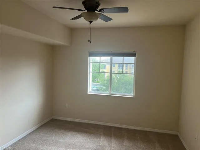 Carpeted spare room featuring baseboards and ceiling fan