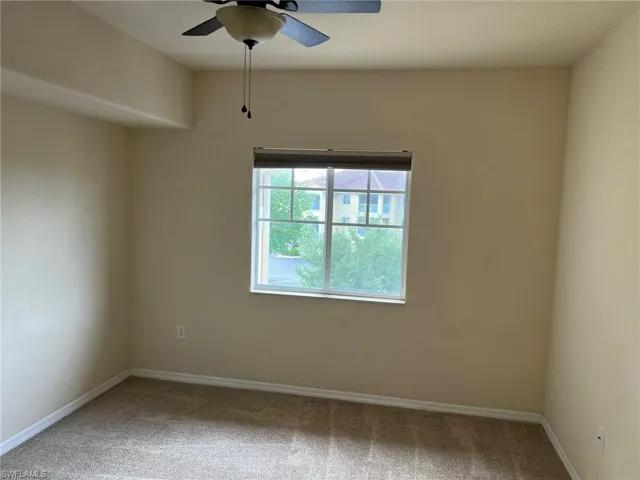 Carpeted empty room featuring baseboards and a ceiling fan