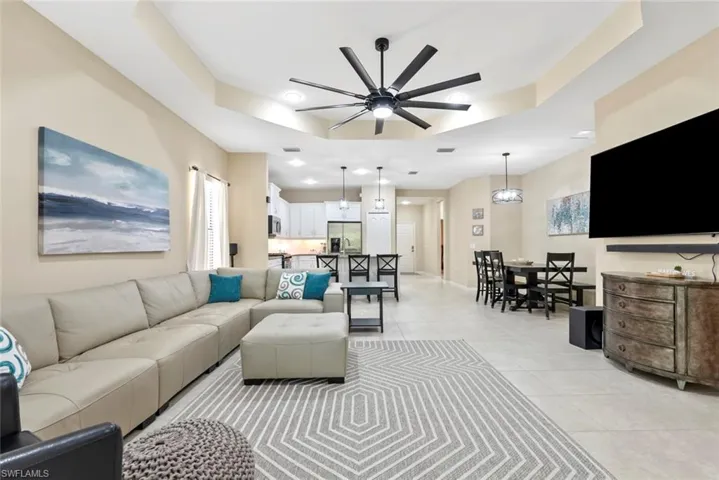 Tiled living room featuring ceiling fan and a raised ceiling