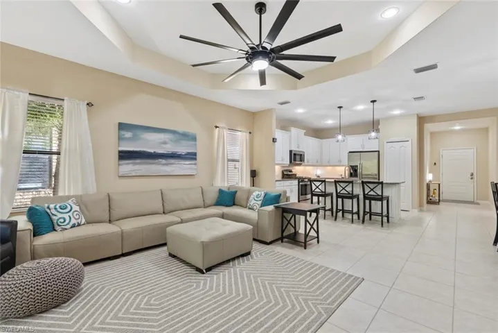 Tiled living room featuring ceiling fan and a tray ceiling