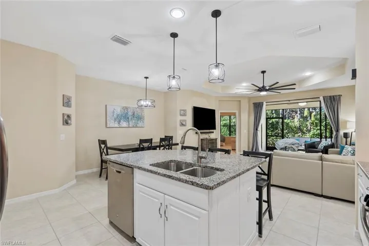 Kitchen featuring sink, dishwasher, an island with sink, white cabinets, and a raised ceiling