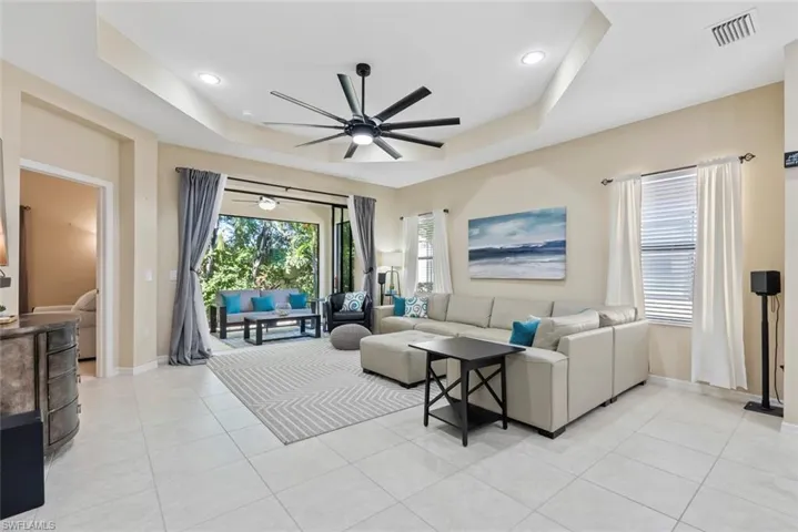 Tiled living room with a raised ceiling and ceiling fan