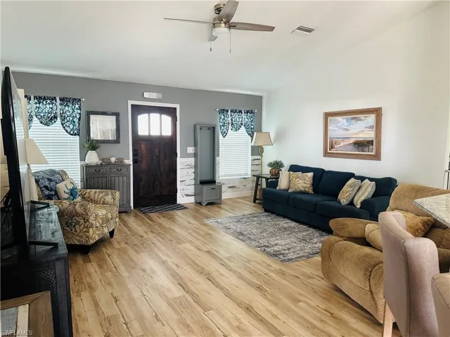 Living area featuring ceiling fan, light wood finished floors, and lofted ceiling