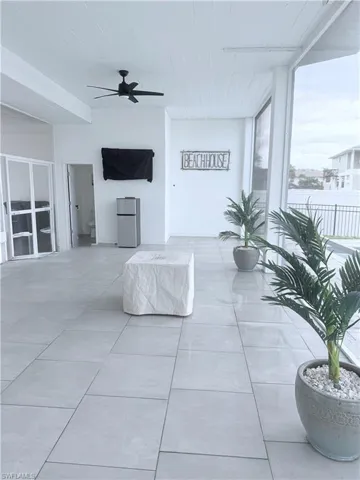 Tiled living room featuring a ceiling fan and a wall of windows