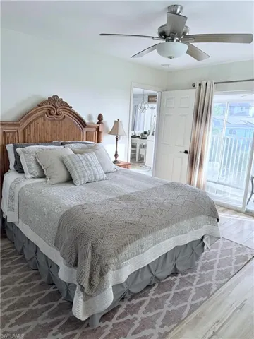 Bedroom with access to exterior, ceiling fan, wood finished floors, and ensuite bath