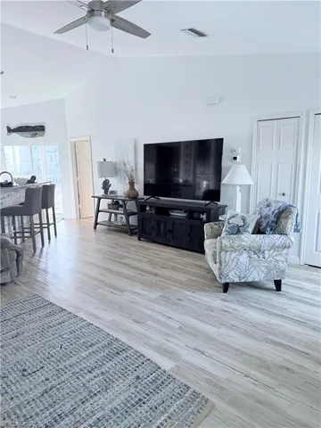 Living area with vaulted ceiling, light wood-type flooring, and ceiling fan