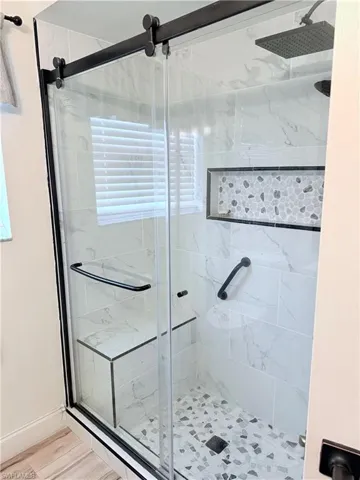 Bathroom with a marble finish shower and baseboards