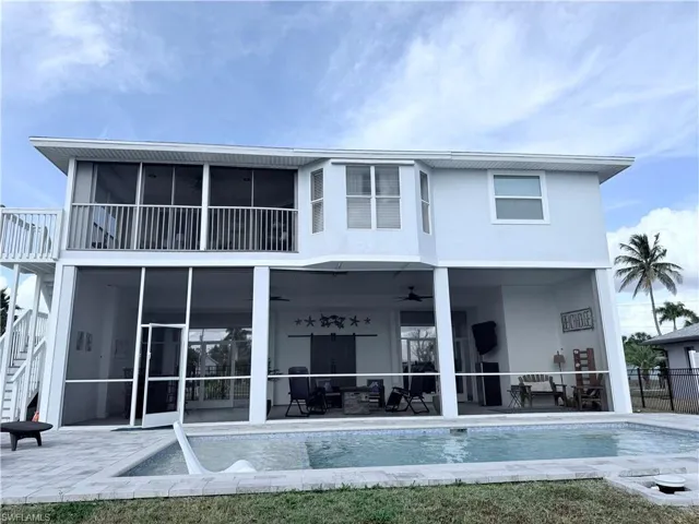 Rear view of property featuring a sunroom, a ceiling fan, an outdoor pool, and stairway