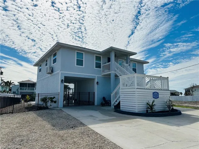 Beach home with stairway, driveway, and a balcony