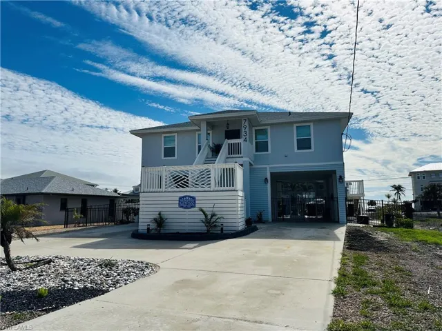 View of front of property featuring driveway, a balcony, stairway, and an attached garage