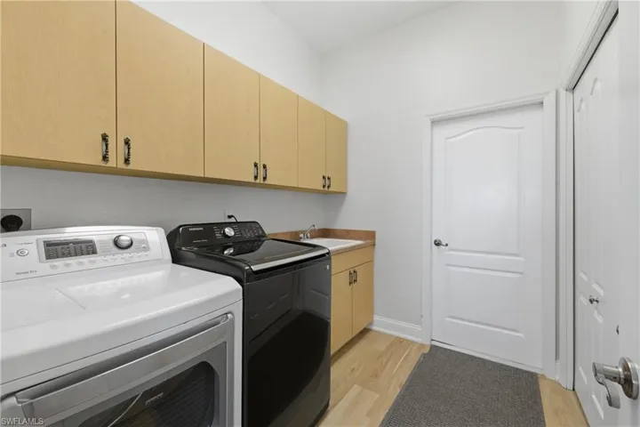 Laundry room with light wood-type flooring, cabinet space, and washing machine and clothes dryer
