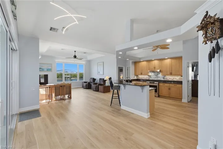 Kitchen with a kitchen bar, open floor plan, decorative backsplash, a ceiling fan, and electric stove