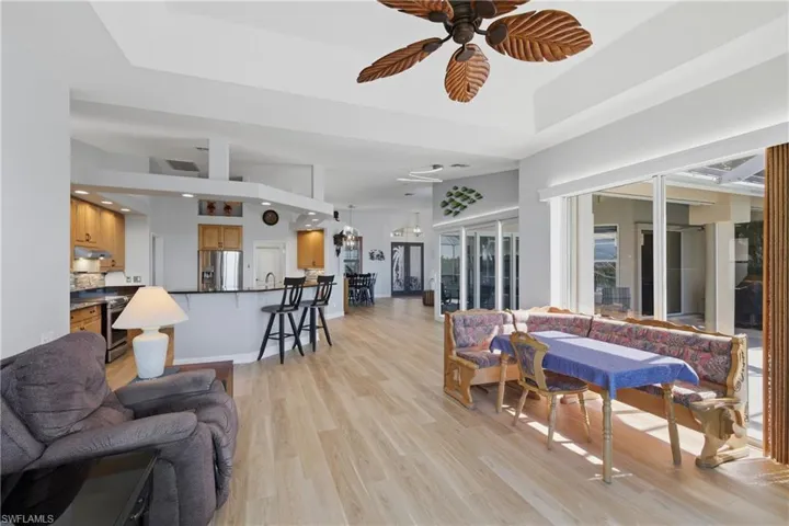 Family area with a ceiling fan, light wood finished floors, and a tray ceiling