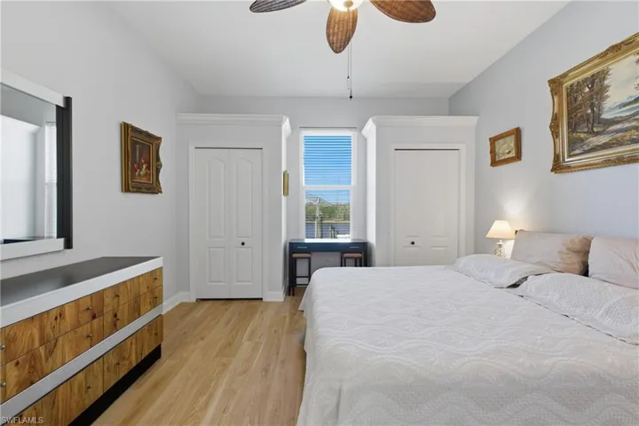 Bedroom with two closets, light wood-style flooring, and ceiling fan