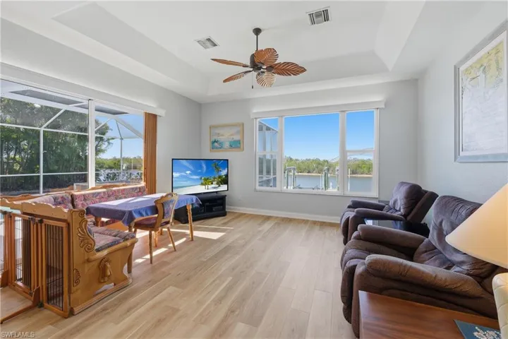 Living area featuring , a tray ceiling, a ceiling fan, and a sunroom