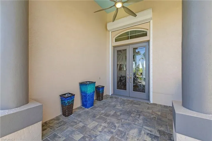 Doorway to property featuring french doors, stucco siding, and a ceiling fan