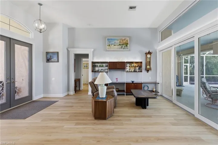 Entrance foyer with french doors, light luxury vinyl floors, a high ceiling, and hanging lights