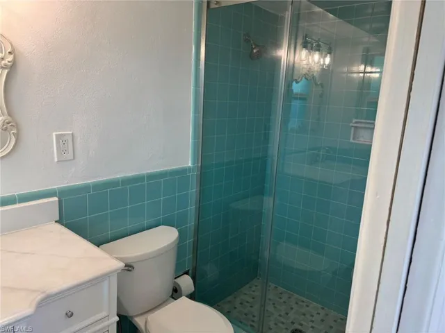 Primary Bath features a tiled walk-in shower with glass shower doors.