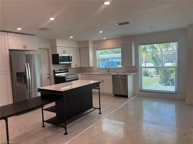 The Kitchen features complete stainless-steel appliances, deep stainless sink, tile plank floor and recessed lighting. Large side window is great spot for computer desk, plants or dining