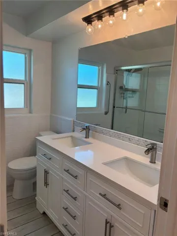 Guest Bath features a dual sink vanity with storage, a linen closet and a combination tub/shower with glass sliding shower doors.