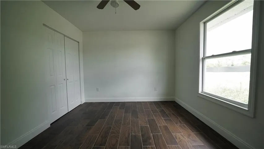 Unfurnished bedroom with dark wood finished floors, baseboards, and a closet
