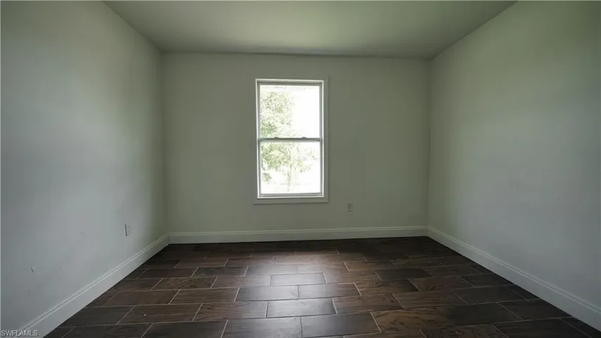 Unfurnished room featuring baseboards and wood finish floors