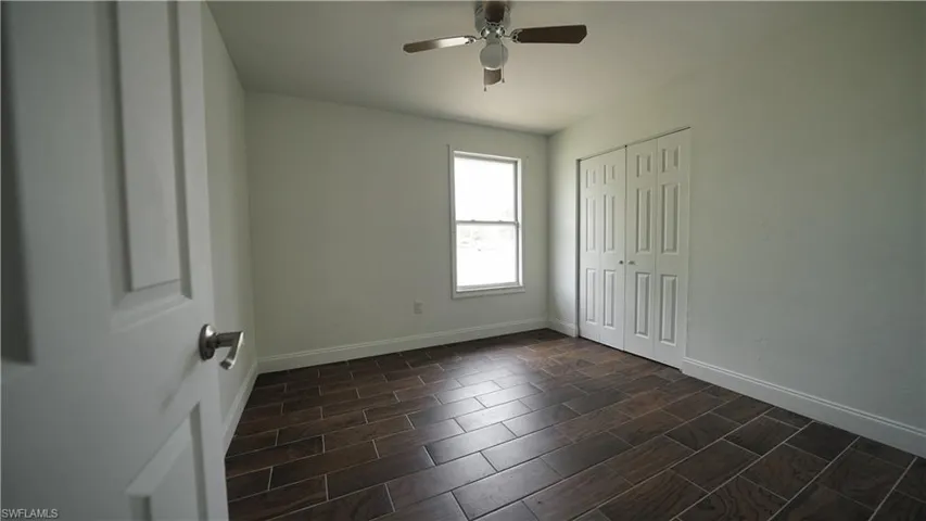 Unfurnished bedroom featuring baseboards, a closet, wood tiled floors, and ceiling fan