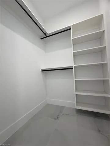 Spacious closet featuring light marble finish floors