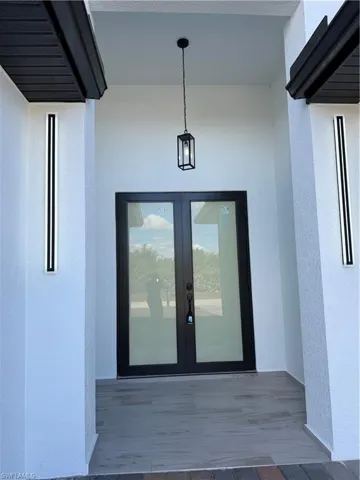 View of exterior entry with stucco siding and french doors