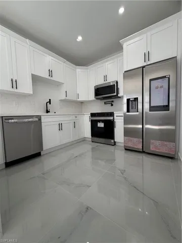 Kitchen featuring white cabinetry, fridge, dishwashing machine, stove, and stainless steel microwave