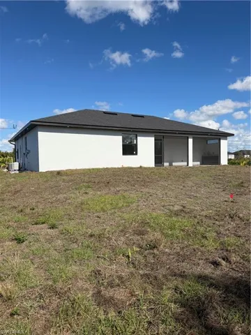 Back of property featuring a lawn, stucco siding, and roof with shingles