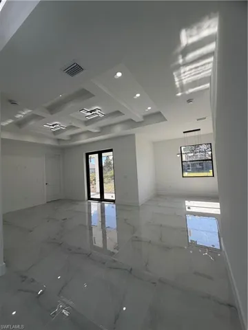 Spare room featuring coffered ceiling, light marble finish floors, recessed lighting, and beamed ceiling