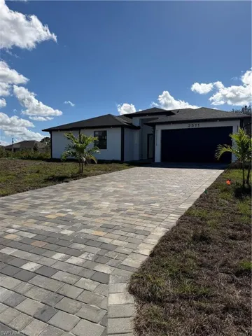 Prairie-style house featuring decorative driveway, stucco siding, and a garage