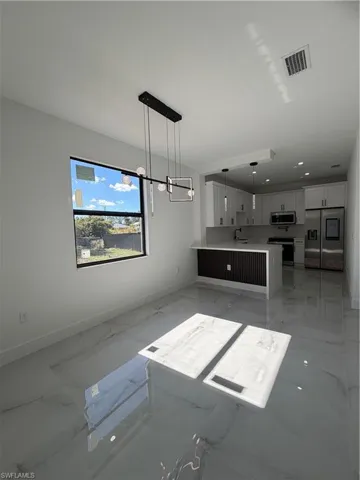Unfurnished living room featuring light marble finish flooring and baseboards