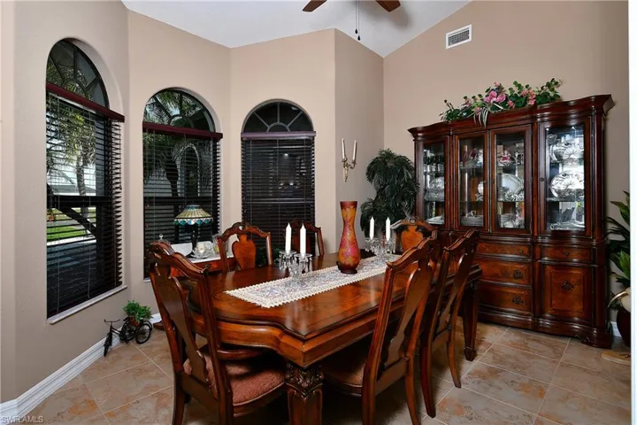 Tiled dining room with lofted ceiling and ceiling fan