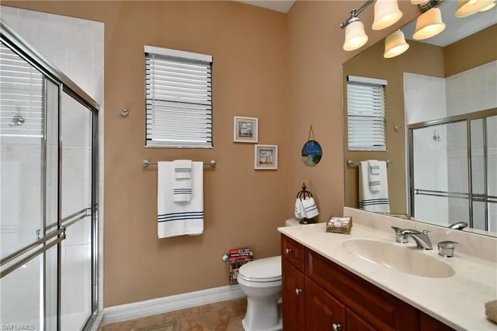 Bathroom with plenty of natural light, an enclosed shower, vanity, and toilet
