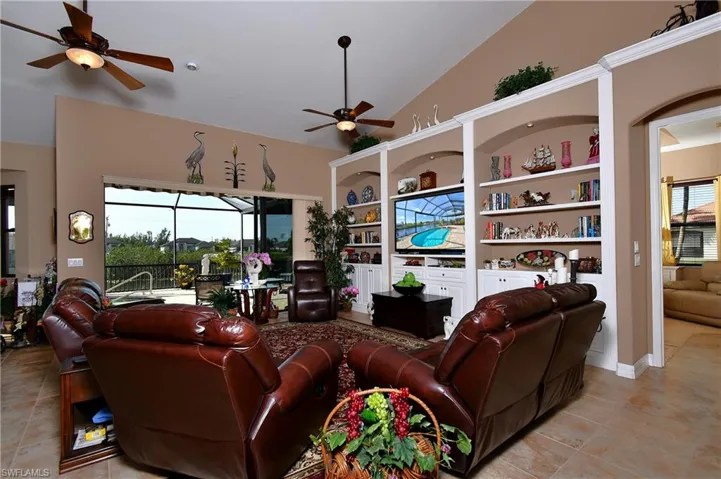 Tiled living room featuring ceiling fan, lofted ceiling, and built in shelves