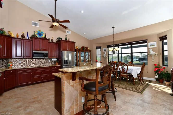 Kitchen featuring a kitchen island with sink, light stone countertops, sink, appliances with stainless steel finishes, and a kitchen bar