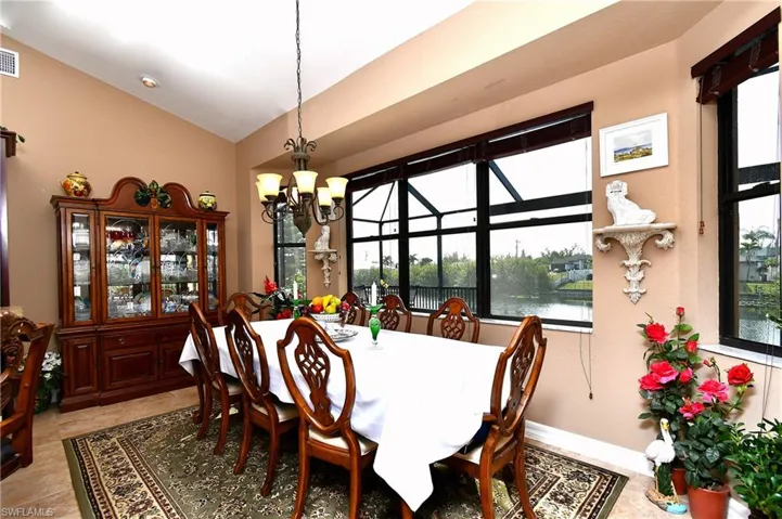 Dining room with a water view, plenty of natural light, an inviting chandelier, and lofted ceiling