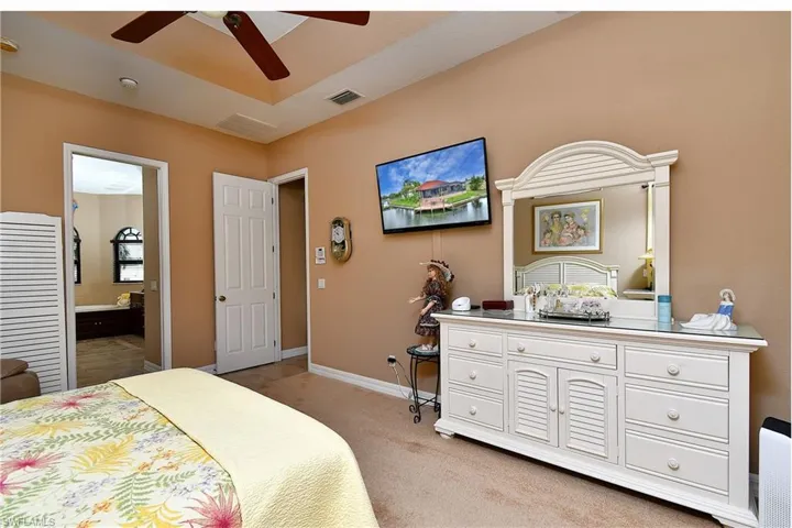 Bedroom featuring ceiling fan, connected bathroom, and light colored carpet