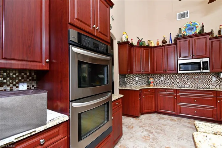 Kitchen with appliances with stainless steel finishes, decorative backsplash, and light stone countertops
