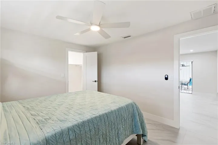 Bedroom featuring light marble finish floors, ceiling fan, and a walk in closet